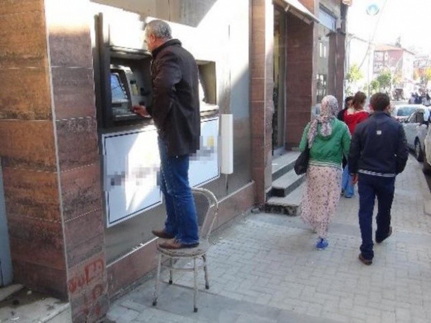 Bartın'da bir banka şubesinin geçici olarak hizmet verdiği binada ATM’ler rahatlıkla erişilemeyecek yükseklikte kalınca, bazı vatandaşlar sandalyenin üzerine çıkarak işlemlerini yapıp para çekti.